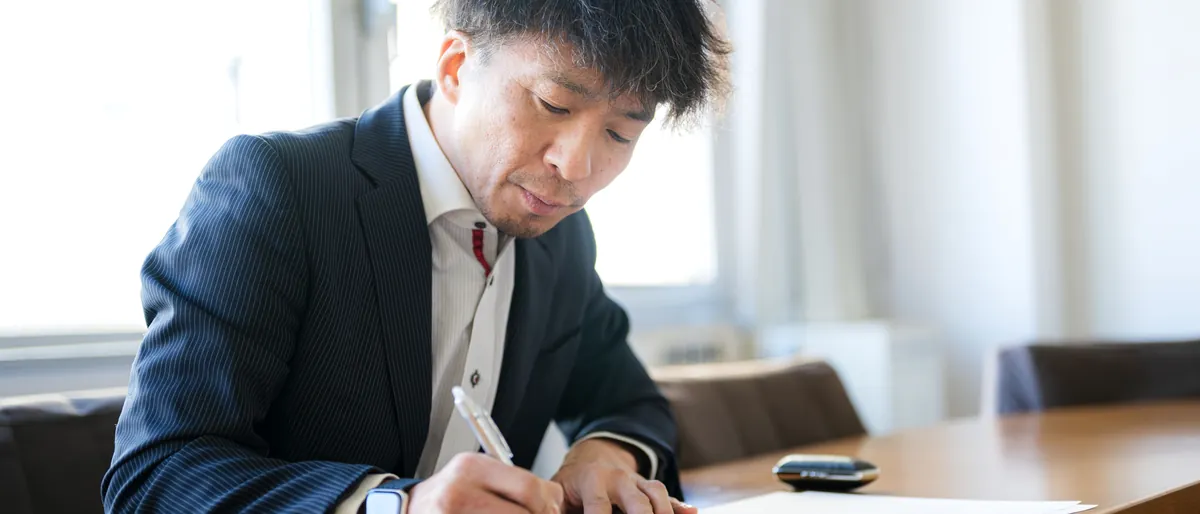 窓際で開示資料を確認し赤入れするIR担当者